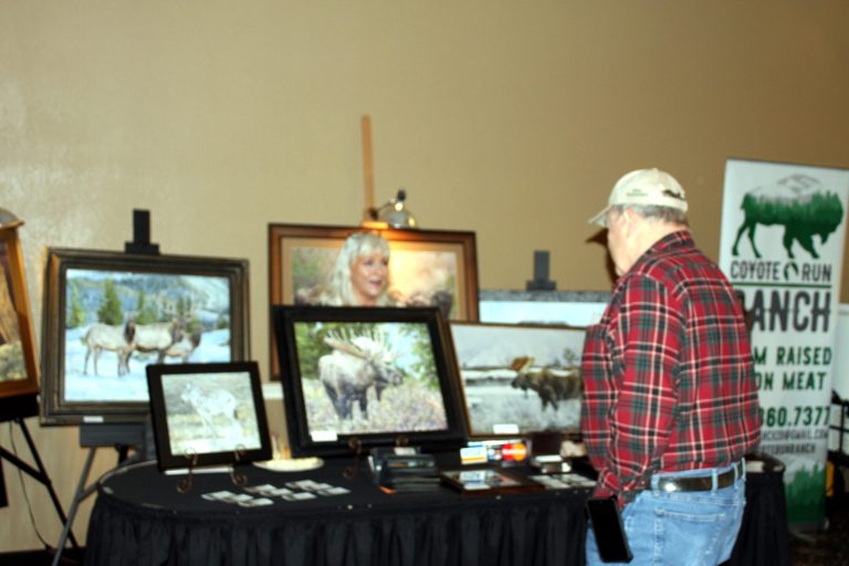 Guest browsing framed wildlife art at the auction tables